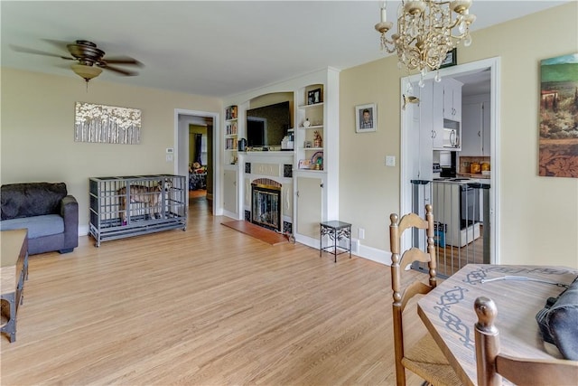 5978 State Route 21st Hwy, Williamson, NY 14589 - living area featuring light wood finished floors, a chandelier, a glass covered fireplace, ceiling fan, and built in features