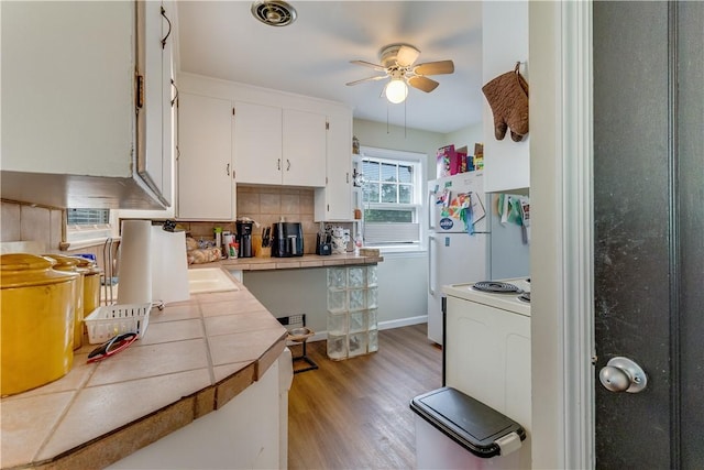 5978 State Route 21st Hwy, Williamson, NY 14589 - kitchen with tile countertops, range with electric stovetop, a ceiling fan, white cabinets, and light wood finished floors