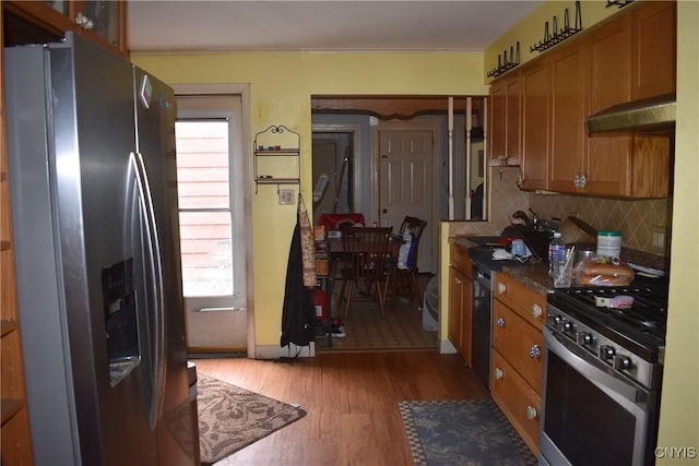 20 E Main St, Cortland, NY 13045 - kitchen featuring appliances with stainless steel finishes, exhaust hood, brown cabinetry, and wood finished floors