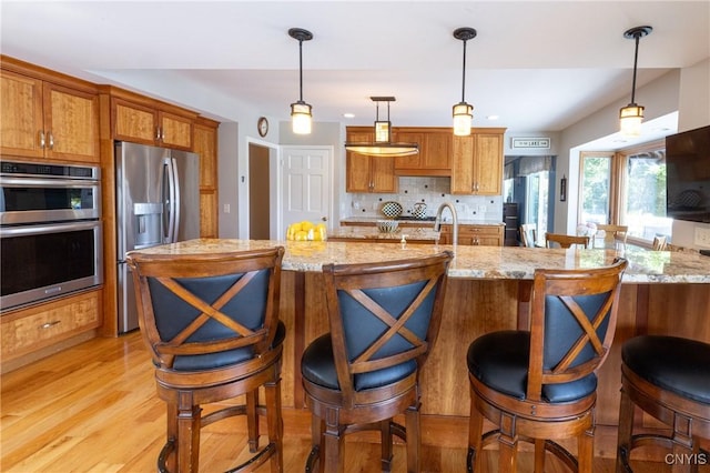 2516 W Lake Rd, Skaneateles, NY 13152 - kitchen with stainless steel appliances, decorative backsplash, brown cabinets, and light wood-style flooring