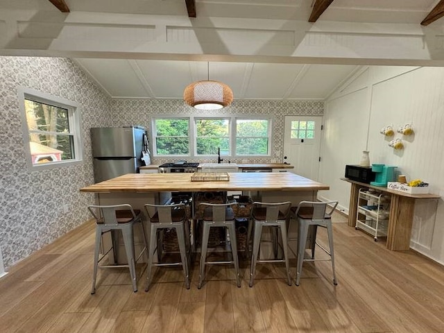 1737 Tupper Hill Rd, Franklin, NY 13775 - kitchen with light wood-type flooring, freestanding refrigerator, wallpapered walls, a kitchen island, and a kitchen breakfast bar