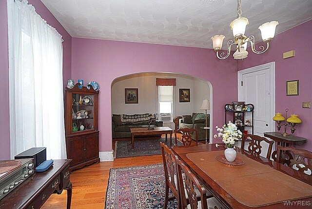 57 Christiana St, North Tonawanda, NY 14120 - dining room with arched walkways, a chandelier, light wood-style flooring, and a textured ceiling