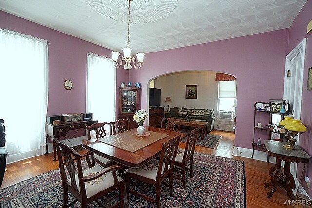 57 Christiana St, North Tonawanda, NY 14120 - dining room featuring arched walkways, wood finished floors, a chandelier, and cooling unit