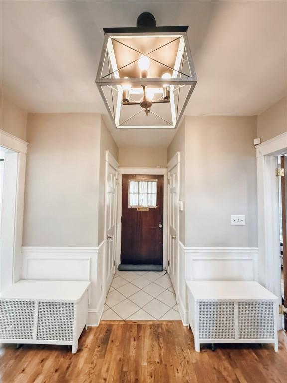 459 W Water St, Elmira City, NY 14905 - foyer featuring a chandelier, wood finished floors, a wainscoted wall, radiator heating unit, and a decorative wall