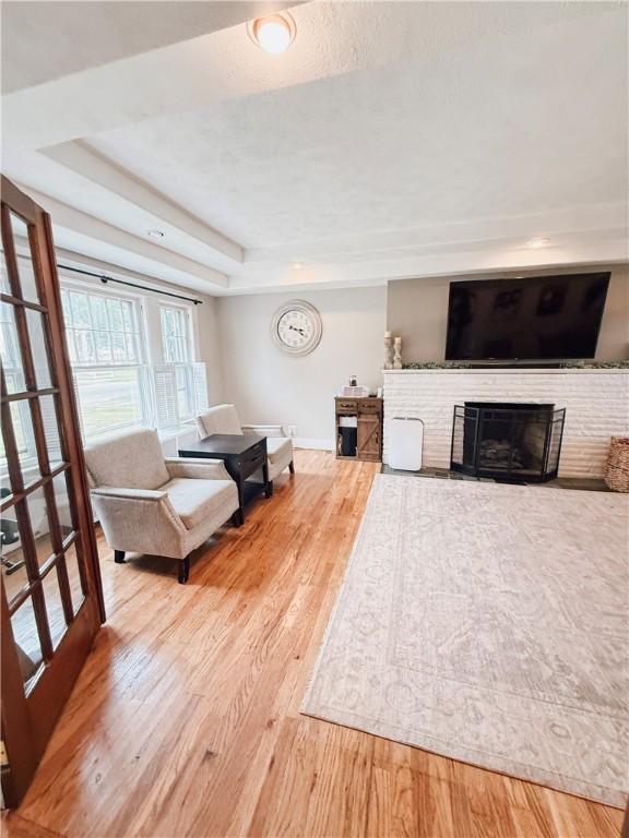 459 W Water St, Elmira City, NY 14905 - living area featuring wood finished floors, a raised ceiling, and a brick fireplace