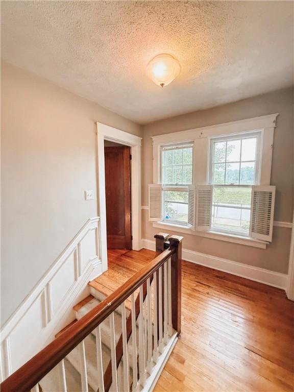 459 W Water St, Elmira City, NY 14905 - hallway with a textured ceiling, light wood-style flooring, and an upstairs landing