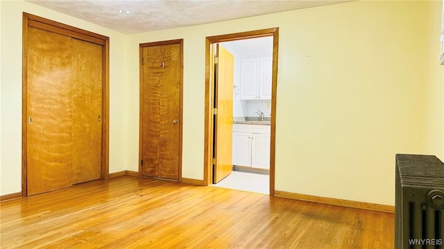 350 S 2nd St, Lewiston, NY 14092 - unfurnished bedroom featuring light wood-type flooring, radiator heating unit, connected bathroom, and a closet