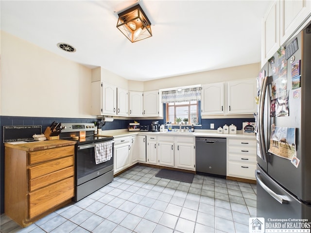 709 Main St, Olean, NY 14760 - kitchen with stainless steel appliances, white cabinetry, light tile patterned flooring, and light countertops