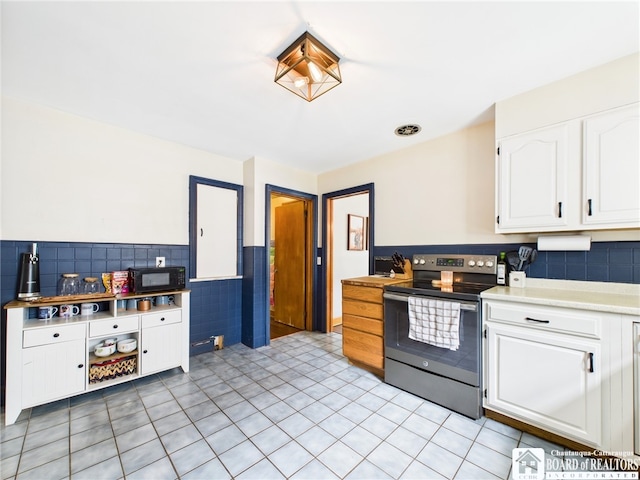 709 Main St, Olean, NY 14760 - kitchen with electric range, tile walls, white cabinets, light countertops, and black microwave