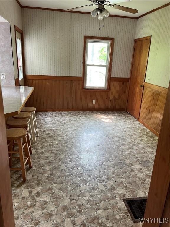 4535 Holley Byron Rd, Clarendon, NY 14470 - unfurnished dining area featuring a ceiling fan, wainscoting, ornamental molding, stone finish floors, and wooden walls