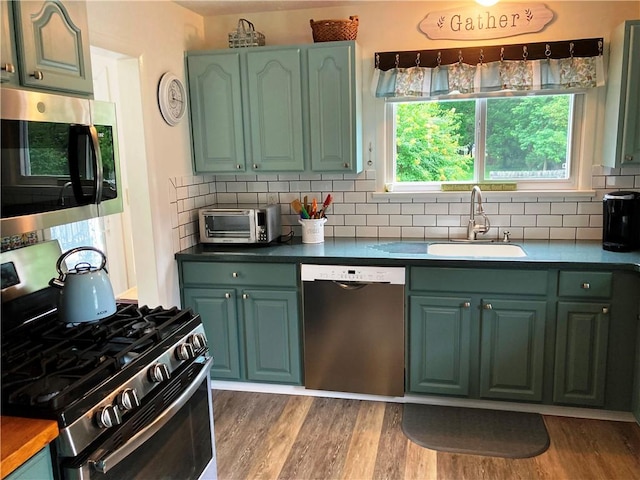 74 Cleveland Ave, Elmira, NY 14905 - kitchen with stainless steel appliances, green cabinetry, decorative backsplash, and wood finished floors