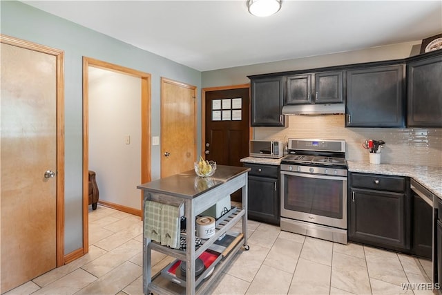 4024 Bond St, Hamburg, NY 14219 - kitchen with stainless steel range with gas cooktop, under cabinet range hood, backsplash, and light tile patterned flooring