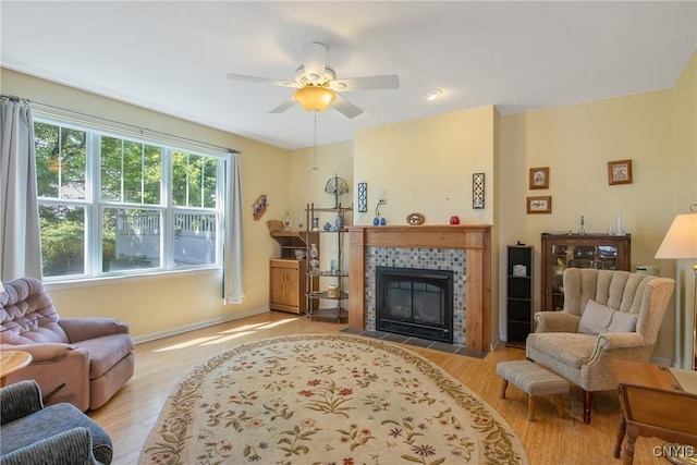 12 Village View Dr, Tully, NY 13159 - living room featuring wood finished floors, a tiled fireplace, and a ceiling fan