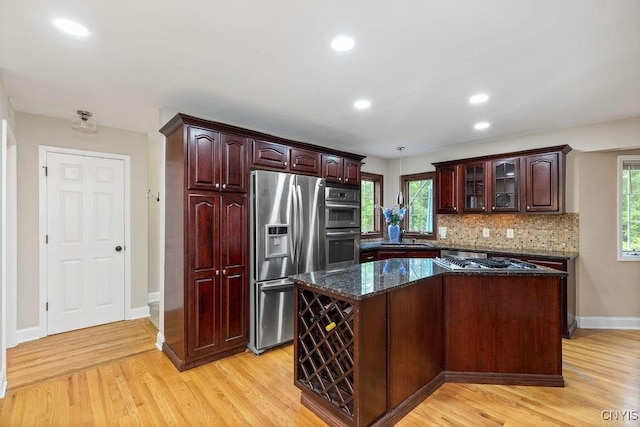 3306 Glen Abbey, Lysander, NY 13135 - kitchen with stainless steel appliances, light wood-type flooring, decorative backsplash, glass insert cabinets, and a center island