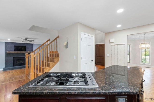 3306 Glen Abbey, Lysander, NY 13135 - kitchen with stainless steel gas cooktop, a fireplace, a ceiling fan, open floor plan, and a center island