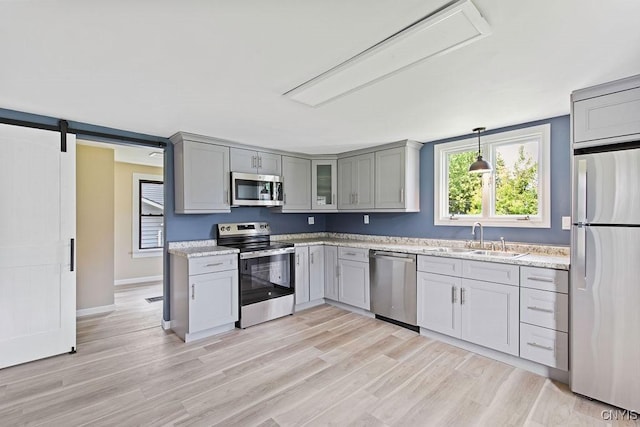 81 E 10th St, Oswego, NY 13126 - kitchen featuring appliances with stainless steel finishes, gray cabinetry, light wood-style floors, hanging light fixtures, and glass insert cabinets
