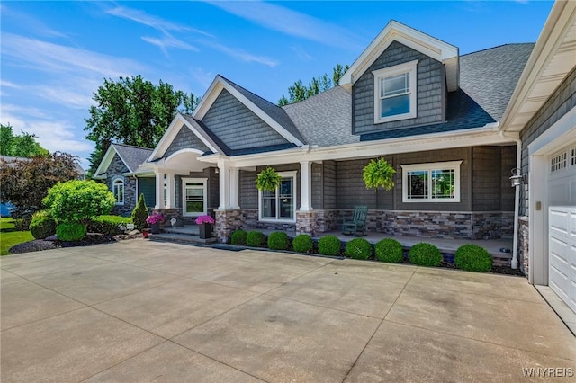 4614 Vrooman Dr, Lewiston, NY 14092 - craftsman-style house featuring a porch, a shingled roof, stone siding, and driveway