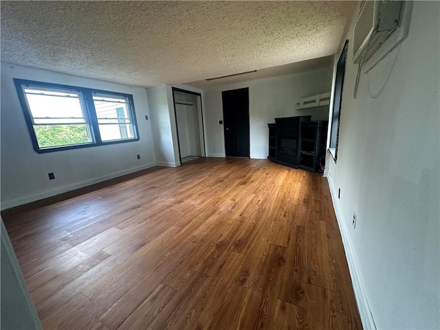 8557 Reeds Corners Rd, Sparta, NY 14437 - unfurnished bedroom featuring wood finished floors, a textured ceiling, and an AC wall unit