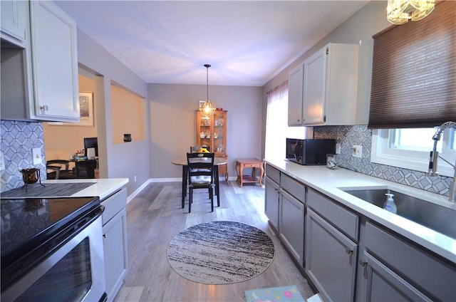 122 Thorn Apple Ln, Greece, NY 14626 - kitchen with stainless steel electric stove, black microwave, light wood-style flooring, backsplash, and light countertops