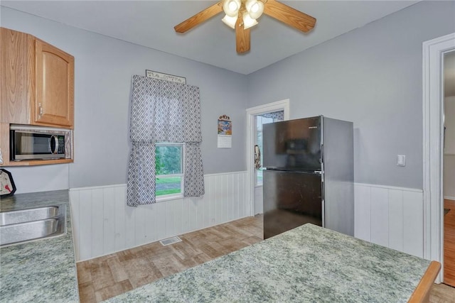 2360 Harris Rd, Palmyra, NY 14522 - kitchen featuring freestanding refrigerator, stainless steel microwave, light wood-style floors, a wainscoted wall, and ceiling fan