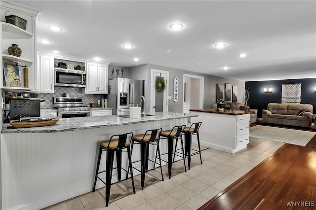 4901 Pineledge Dr W, Clarence, NY 14031 - kitchen featuring appliances with stainless steel finishes, open shelves, white cabinets, a peninsula, and light tile patterned floors