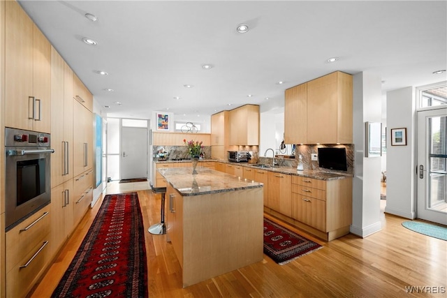 176 Rivermist Dr, Buffalo, NY 14202 - kitchen with stainless steel oven, light stone counters, light wood-style flooring, a center island, and light brown cabinets