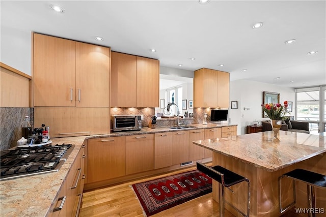 176 Rivermist Dr, Buffalo, NY 14202 - kitchen featuring stainless steel gas stovetop, a breakfast bar, backsplash, light stone counters, and recessed lighting
