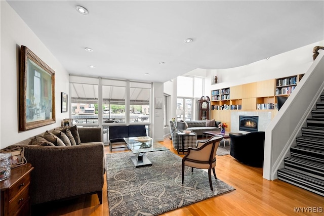 176 Rivermist Dr, Buffalo, NY 14202 - living room with a glass covered fireplace, light wood finished floors, stairs, and recessed lighting