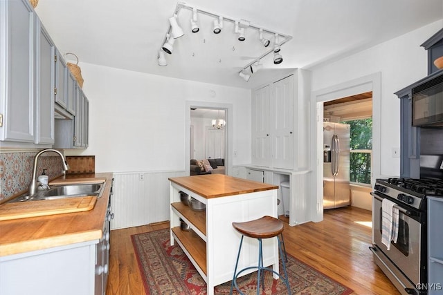 6 Union St, Cazenovia, NY 13035 - kitchen featuring appliances with stainless steel finishes, butcher block counters, open shelves, wood finished floors, and a wainscoted wall