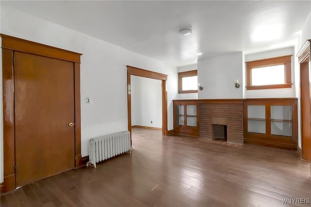 20 Rejtan St, Buffalo, NY 14206 - unfurnished living room featuring radiator heating unit, wood finished floors, and a brick fireplace