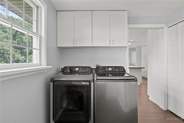 9015 Donahue Rd, Batavia, NY 14020 - washroom featuring separate washer and dryer, cabinet space, wood finished floors, and healthy amount of natural light