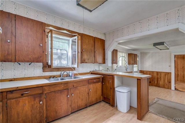 7259 Number Four Rd, Watson, NY 13367 - kitchen with wallpapered walls, brown cabinetry, light wood-style floors, a wainscoted wall, and light countertops