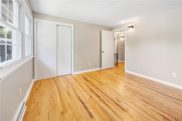 14 Ibis, Clay, NY 13090 - unfurnished bedroom with light wood finished floors, a baseboard heating unit, and a closet