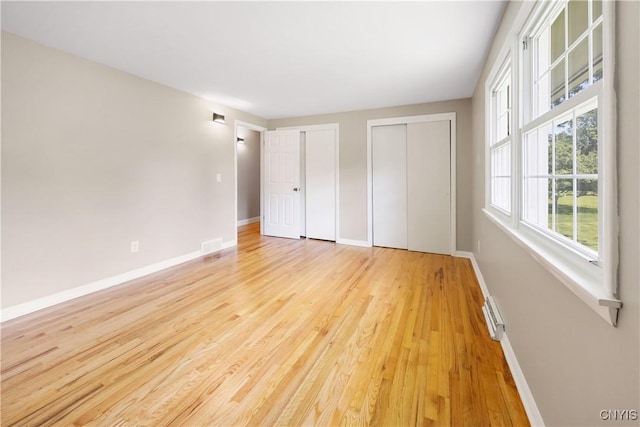 14 Ibis, Clay, NY 13090 - unfurnished bedroom featuring multiple closets, light wood-type flooring, and a baseboard heating unit