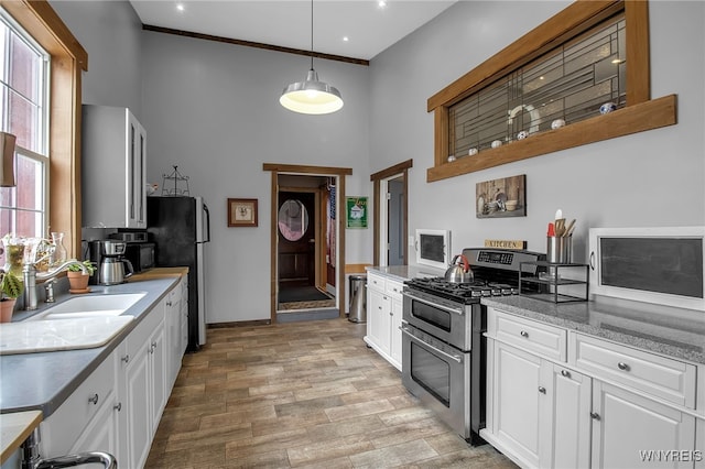 2244 Lockport Olcott Rd, Newfane, NY 14108 - kitchen featuring stainless steel appliances, a towering ceiling, white cabinetry, light wood-type flooring, and pendant lighting