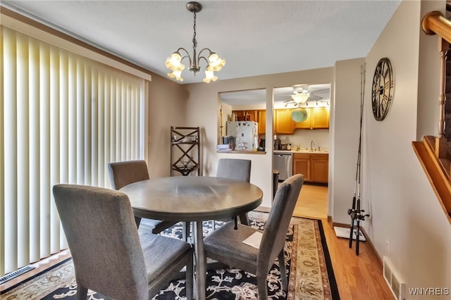 6192 Thornwood Dr, Boston, NY 14075 - dining area with light wood-type flooring, a chandelier, and a ceiling fan