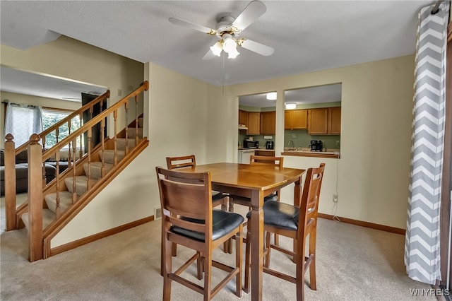 6192 Thornwood Dr, Boston, NY 14075 - dining area with light colored carpet, a ceiling fan, and stairs