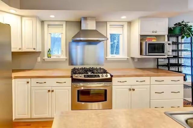 1565 Tupper Hill Rd, Franklin, NY 13775 - kitchen featuring wall chimney exhaust hood, appliances with stainless steel finishes, white cabinetry, and recessed lighting