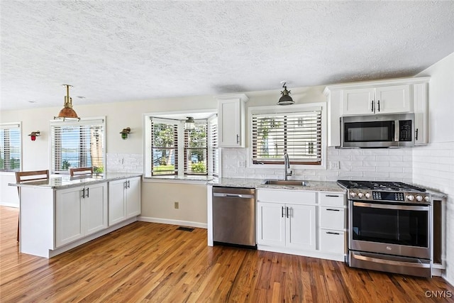2761 E Lake Rd, Skaneateles, NY 13152 - kitchen featuring appliances with stainless steel finishes, wood finished floors, a peninsula, a textured ceiling, and white cabinets