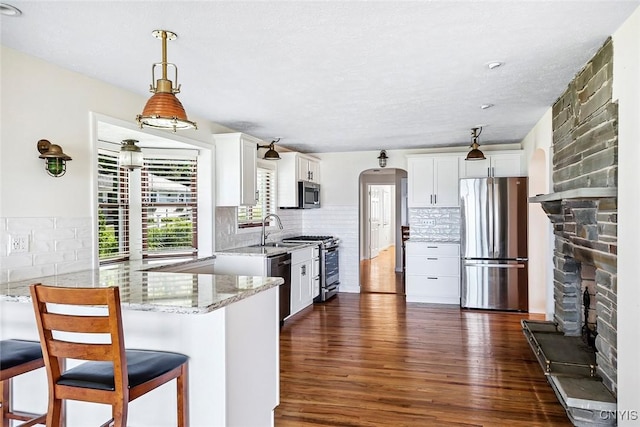 2761 E Lake Rd, Skaneateles, NY 13152 - kitchen featuring stainless steel appliances, dark wood finished floors, a fireplace, light stone countertops, and white cabinets