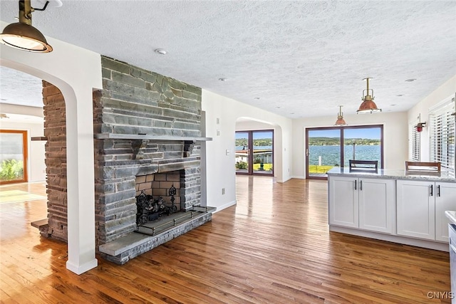 2761 E Lake Rd, Skaneateles, NY 13152 - unfurnished living room with wood finished floors, a textured ceiling, a fireplace, and arched walkways