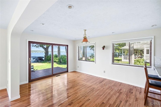 2761 E Lake Rd, Skaneateles, NY 13152 - unfurnished dining area with wood finished floors, arched walkways, a textured ceiling, and recessed lighting