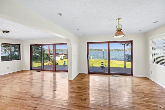 2761 E Lake Rd, Skaneateles, NY 13152 - empty room with wood finished floors, healthy amount of natural light, arched walkways, and a textured ceiling
