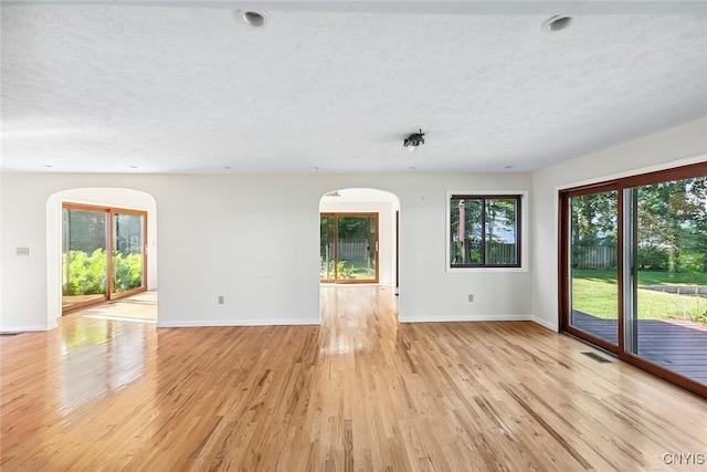 2761 E Lake Rd, Skaneateles, NY 13152 - unfurnished room with arched walkways, a textured ceiling, and light wood finished floors