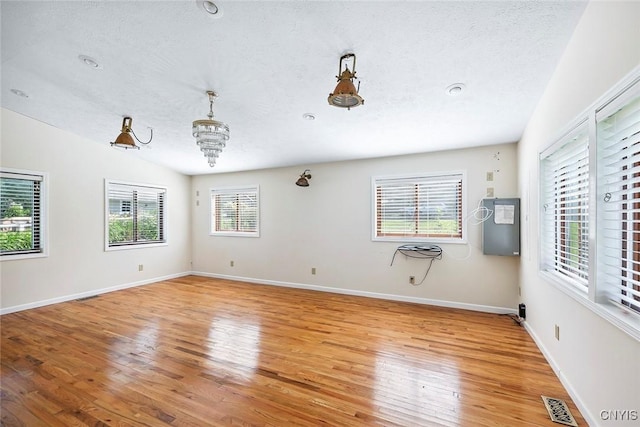2761 E Lake Rd, Skaneateles, NY 13152 - empty room featuring light wood-type flooring, a textured ceiling, a chandelier, and lofted ceiling