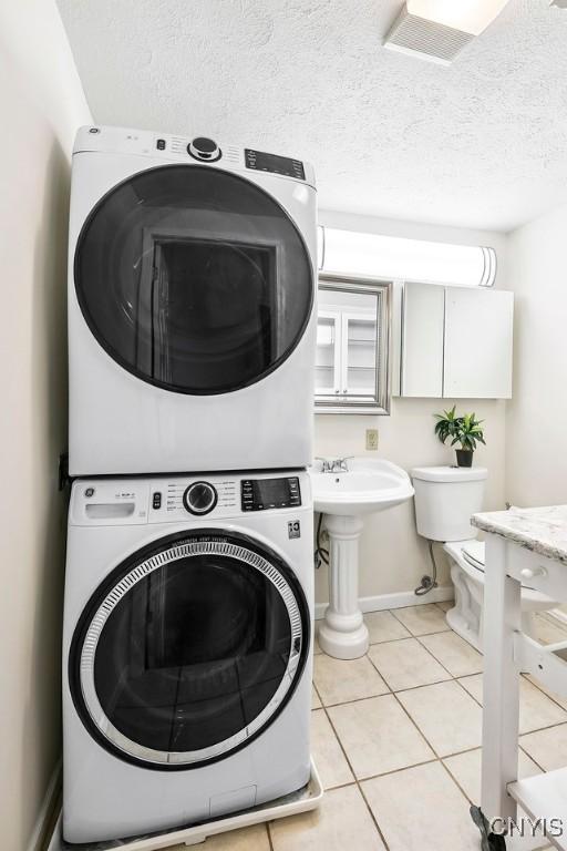 2761 E Lake Rd, Skaneateles, NY 13152 - laundry room with stacked washer / drying machine, light tile patterned floors, and a textured ceiling