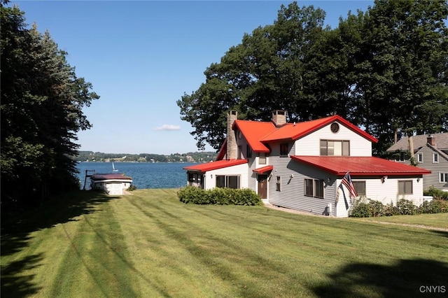 2761 E Lake Rd, Skaneateles, NY 13152 - view of front facade featuring a chimney, a front lawn, a water view, and a metal roof