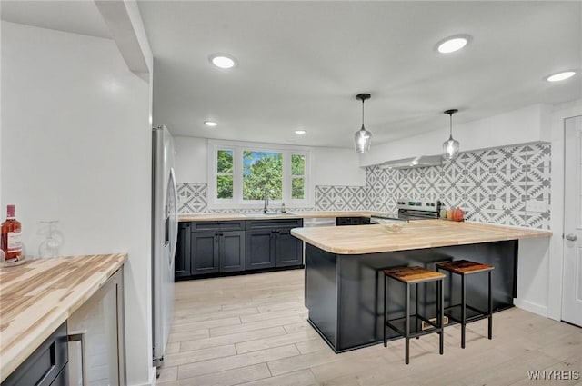 12 Clark St, Perry, NY 14530 - kitchen with butcher block counters, appliances with stainless steel finishes, a breakfast bar, backsplash, and light wood-style flooring