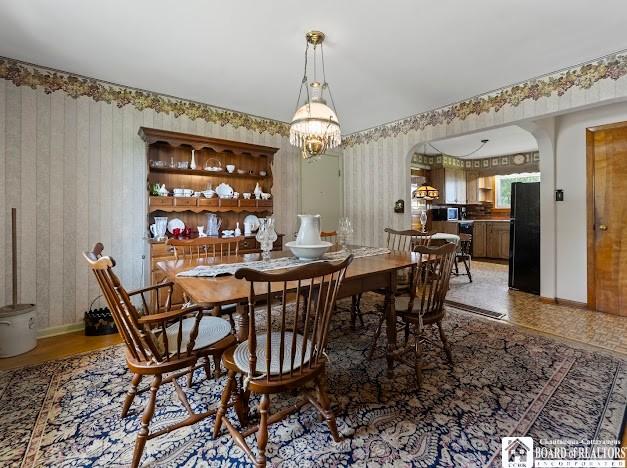 5005 W Main Rd, Pomfret, NY 14063 - dining room featuring arched walkways, wallpapered walls, a chandelier, and light wood finished floors