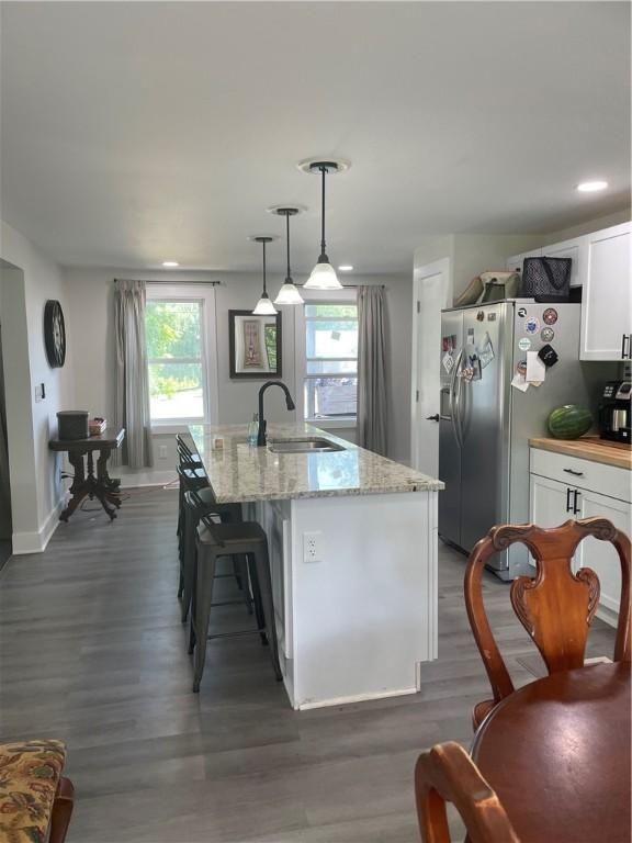 16562 Ridge Rd, Murray, NY 14470 - kitchen featuring stainless steel fridge with ice dispenser, white cabinets, wood finished floors, light stone counters, and pendant lighting